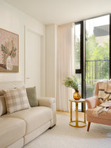 Living room with beige sofa, pink armchair, and a small round table with a vase.