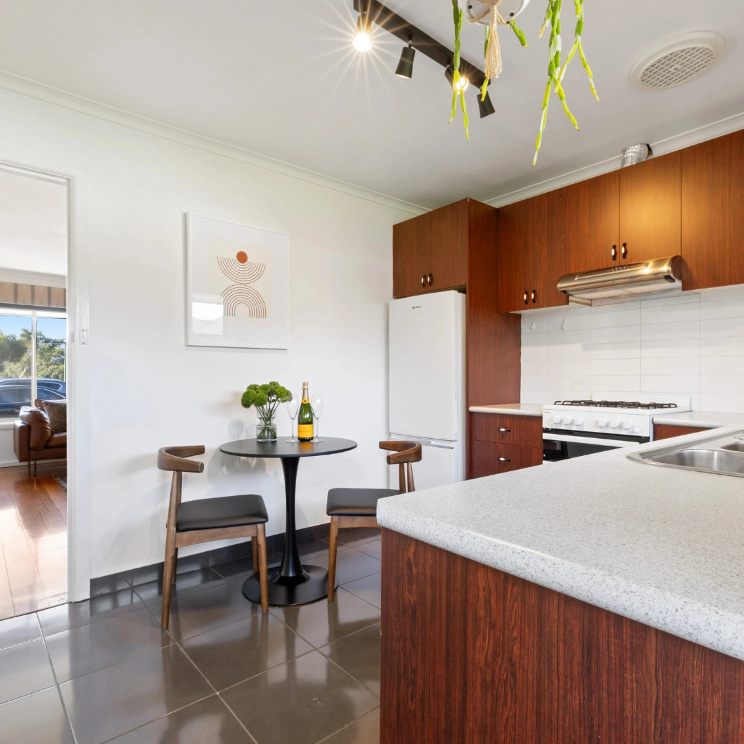 Modern kitchen with wooden cabinets, white appliances, and a small dining area. Property styling, Reservoir.