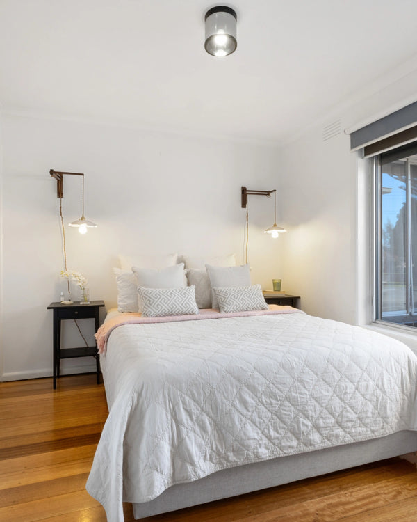 Modern bedroom with a bed, nightstands, and wall lights.