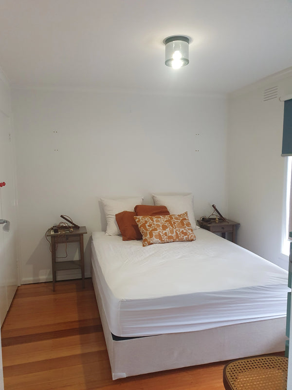 Bedroom with a bed and pillows on a wooden floor.