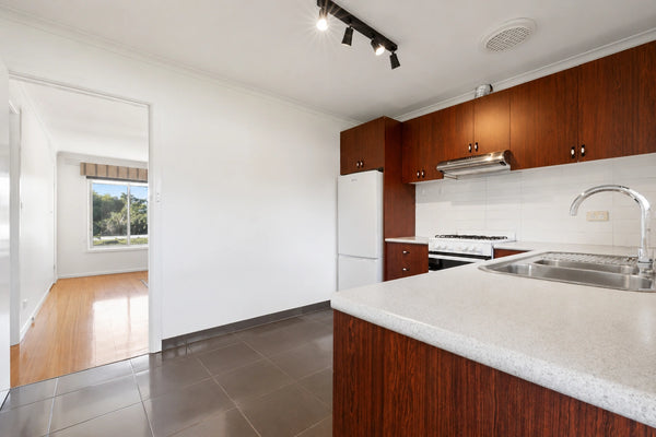 Modern kitchen with wooden cabinets, white countertops, and stainless steel appliances.