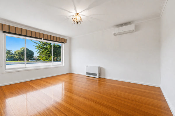 Empty room with wooden flooring, large window, and air conditioning unit.