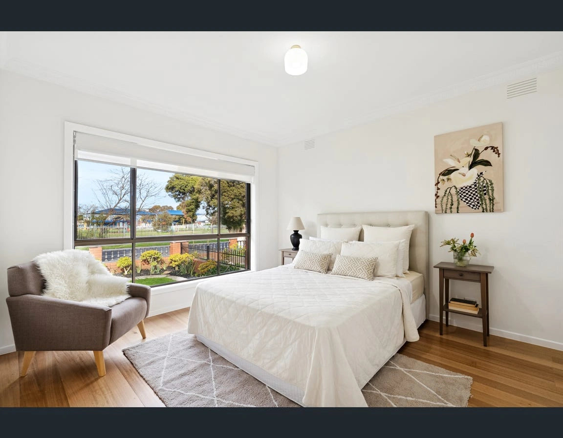 Modern bedroom, Reservoir Victoria styled queen bed, armchair, and large window view. Neutrals and homely softened by a floor rug.